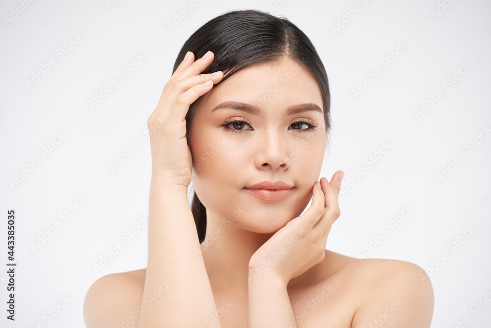 Face of attractive young woman touching her face with beautiful skin and looking at camera