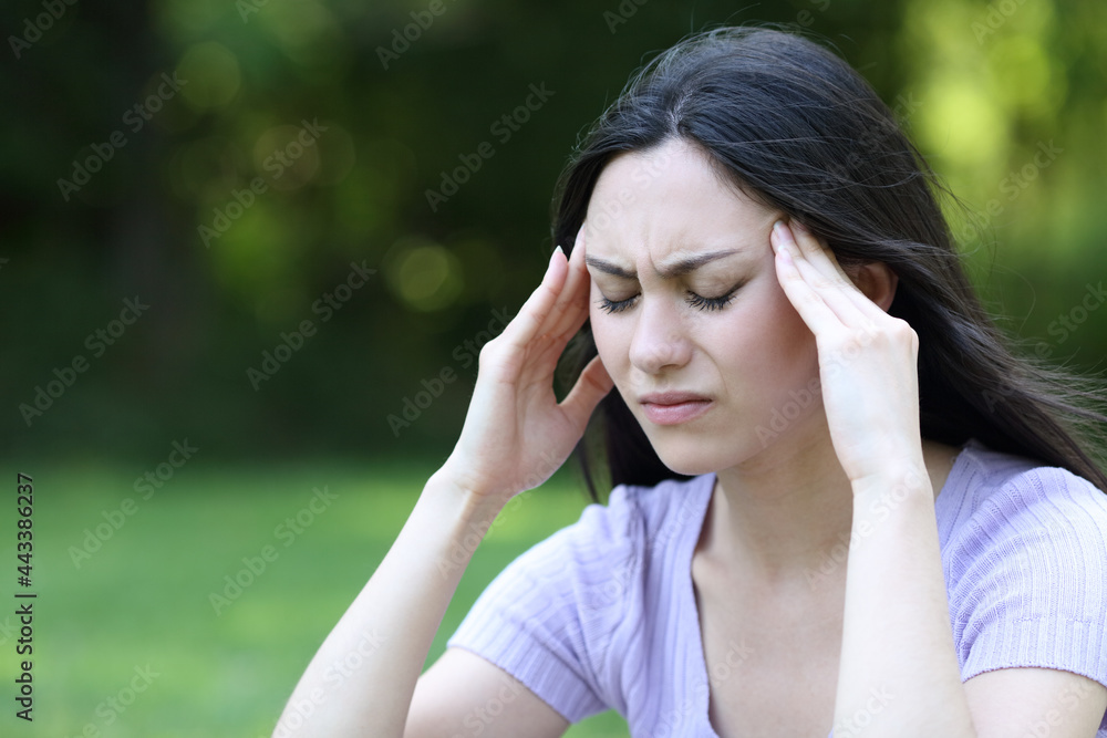 Asian woman suffering migraine in a park Asian woman suffering migraine in a park