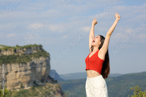 Excited asian woman celebrating in the mountain