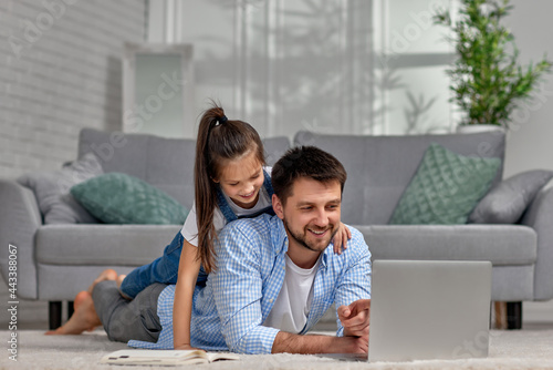 little child girl and handsome father using laptop