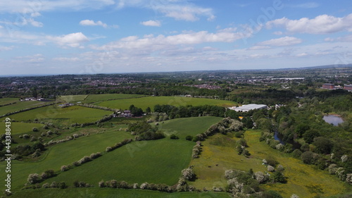 Drone image looking over green farmland with a cloudy sky background. 
