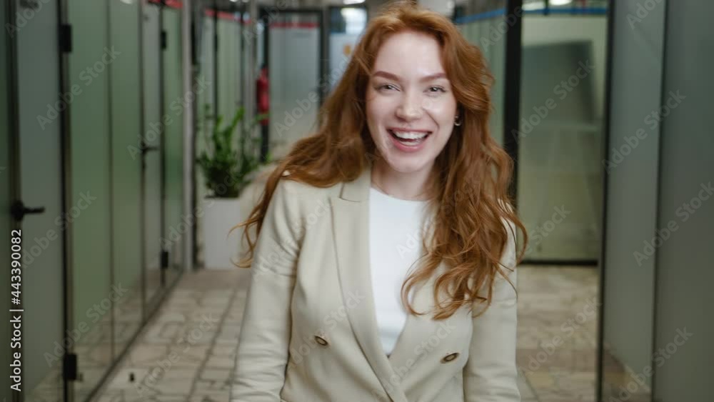 Young happy female business manager wearing formal suit dancing in the office. Motivatated funny business lady dancing celebrating successful deal. Redhead woman student enjoy victory dance in office