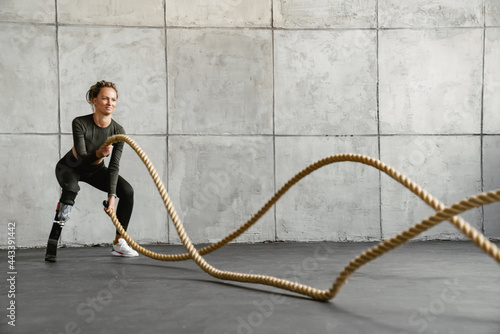 Fototapeta Naklejka Na Ścianę i Meble -  Young sportswoman with prosthesis working out with battle ropes