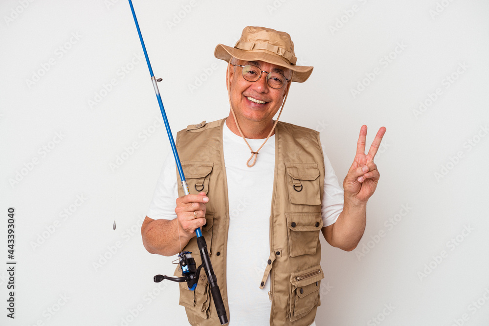 Senior american fisherman holding rod isolated on white background joyful and carefree showing a peace symbol with fingers. Senior american fisherman holding rod isolated on white background joyful and carefree showing a peace symbol with fingers.