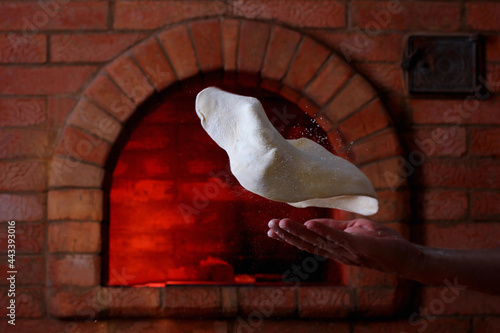 a baker's hand with thrown flour on the background of a preheated cooking oven