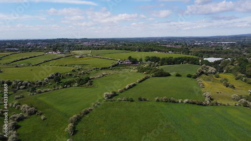 Aerial view over green farmland with a cloudy sky background. 