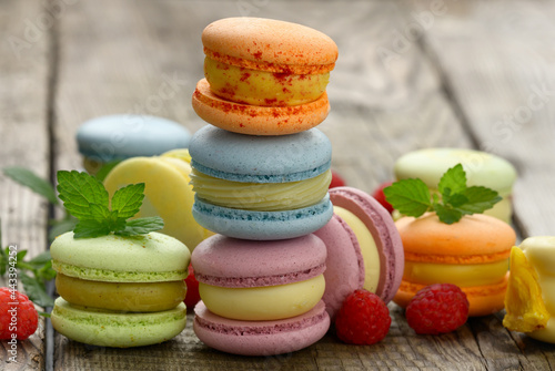stack of baked multicolored macarons and different flavors on a gray wooden table