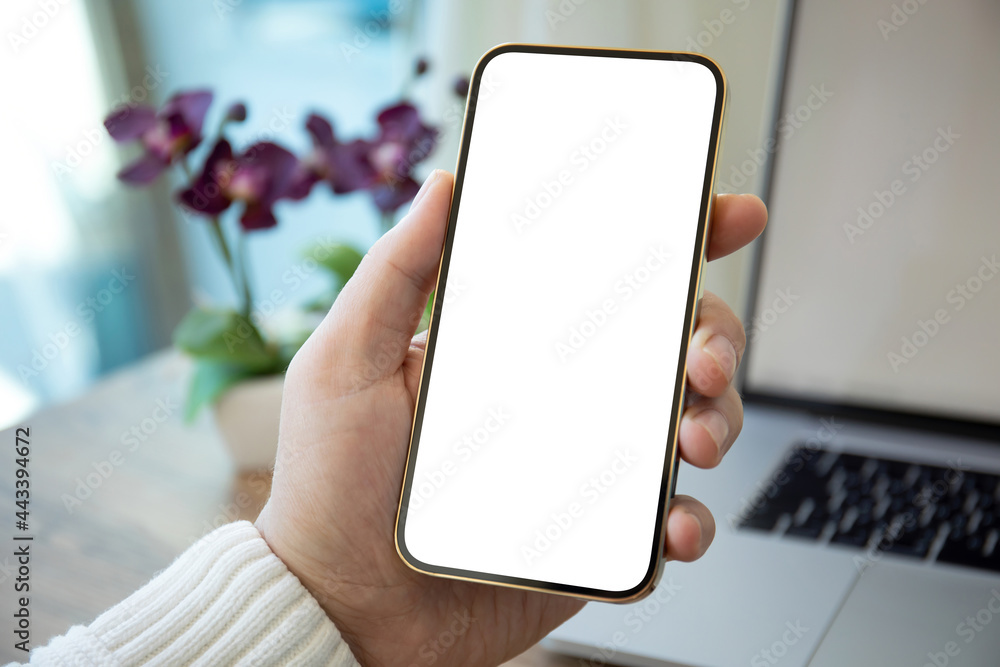 male hands holding phone with isolated screen on background laptop male hands holding phone with isolated screen on background laptop