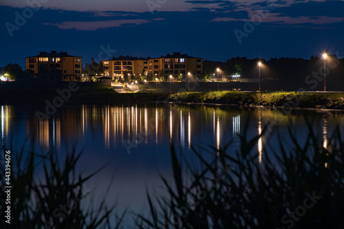 Beach houses at night, reflected light in the water from residential buildings.