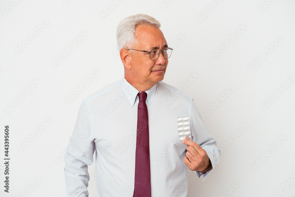 Senior american man holding pills isolated on white background confused, feels doubtful and unsure. Senior american man holding pills isolated on white background confused, feels doubtful and unsure.