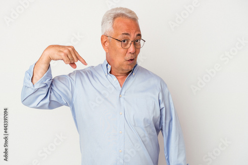 Senior american man isolated on white background person pointing by hand to a shirt copy space, proud and confident © Asier
