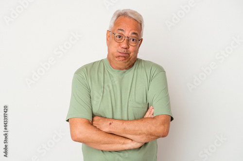 Senior american man isolated on white background blows cheeks, has tired expression. Facial expression concept.