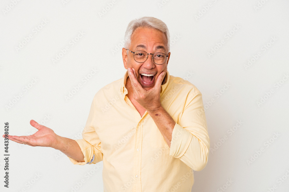 Senior american man isolated on white background holds copy space on a palm, keep hand over cheek. Amazed and delighted. Senior american man isolated on white background holds copy space on a palm, keep hand over cheek. Amazed and delighted.