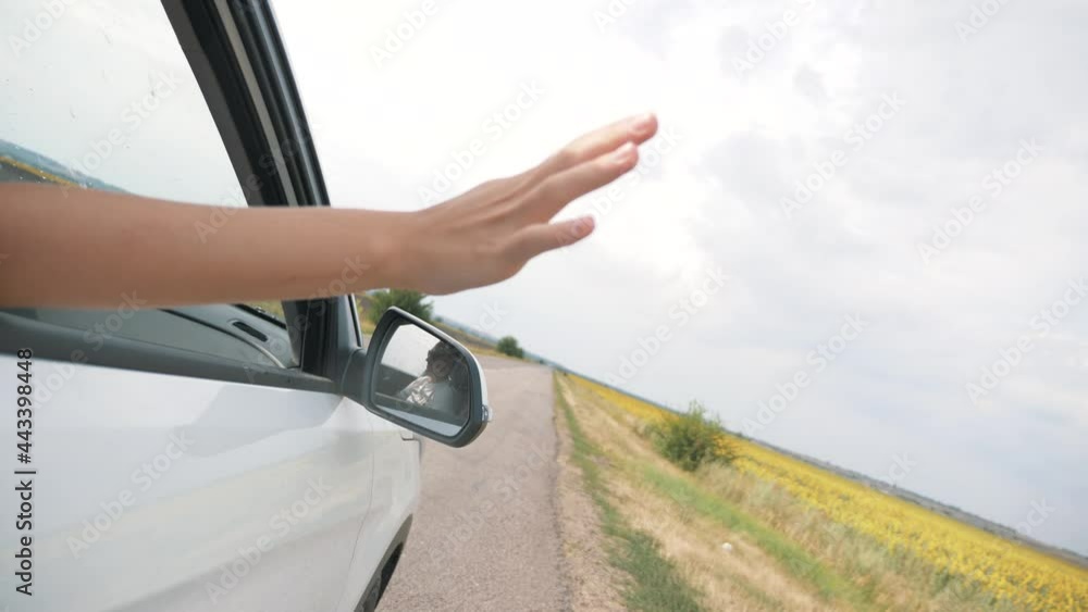 Free young girl enjoying a car ride on a summer day. Close-up woman's hand in the car window. The girl catches the wind with her hand, enjoying the journey and freedom. Traveling by car in summer. Free young girl enjoying a car ride on a summer day. Close-up woman's hand in the car window. The girl catches the wind with her hand, enjoying the journey and freedom. Traveling by car in summer.