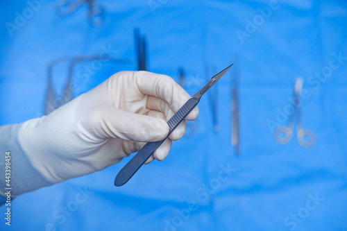 Surgeon holds scalpel in operating theatre