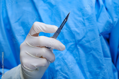 Surgeon holds scalpel in operating theatre