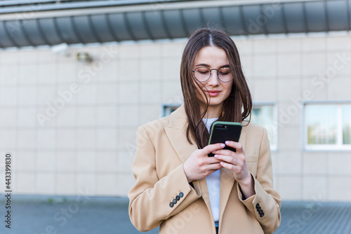 An attractive young woman walking in the city center, texting and laughing. Woman entrepreneur taking a break from work checking her cell phone.