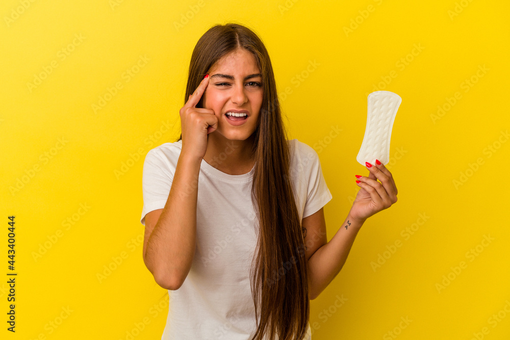 Young caucasian woman holding a compress isolated on yellow background showing a disappointment gesture with forefinger. Young caucasian woman holding a compress isolated on yellow background showing a disappointment gesture with forefinger.