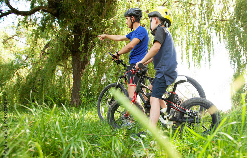 Naklejka premium Father and son together are riding bicycles through the pathway