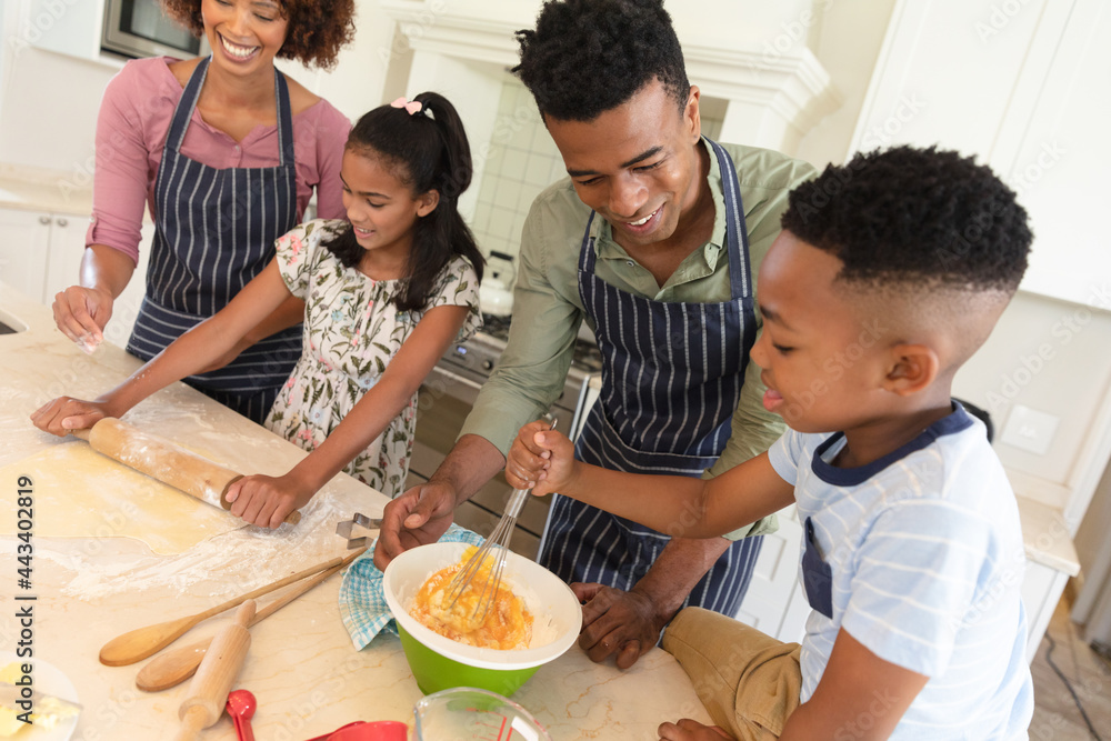 Happy african american parents baking with son and daughter in kitchen