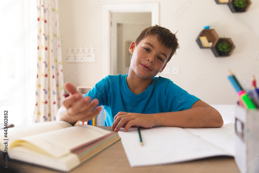 Caucasian boy having video call talking during class, sitting at desk at home Caucasian boy having video call talking during class, sitting at desk at home