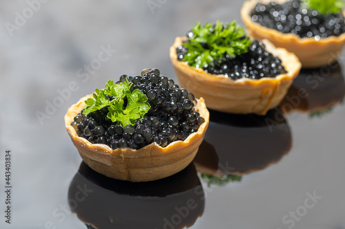 Black caviar in tartlets on a dark background. Healthy food concept.