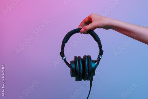 Headphones in a woman's hand on a gradient background