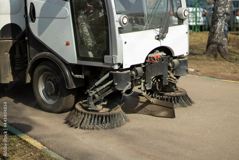The sweeper is sweeping the asphalt. Cleaning the path with a cleaning vehicle.