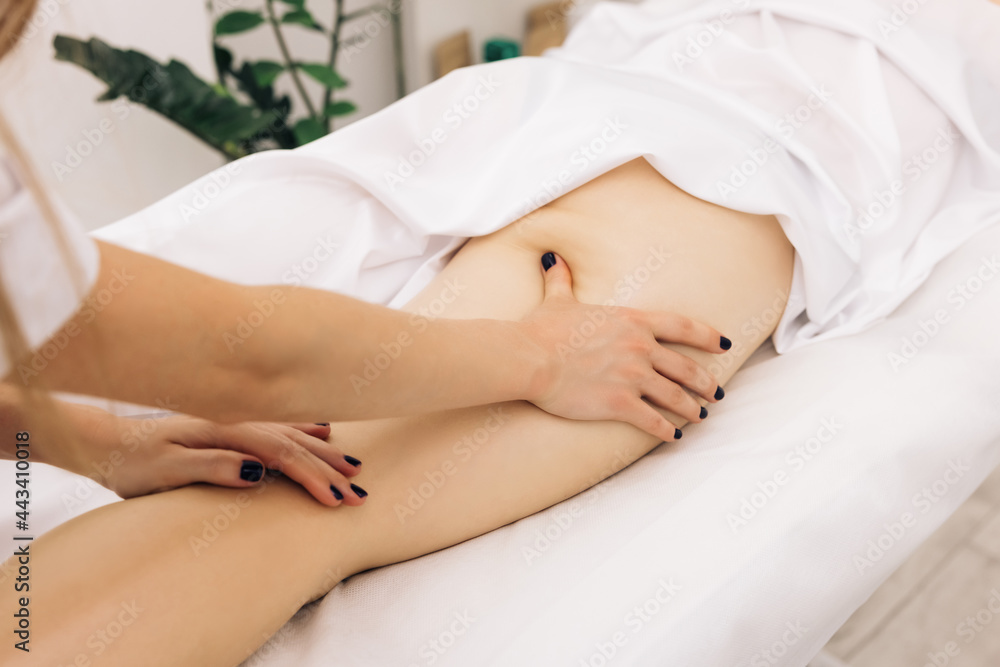 Obraz premium Professional is massaging and touching skin of female client, using traditional techniques. Specialist works with body of patient. Masseur is doing massage of back of woman lying in beauty salon