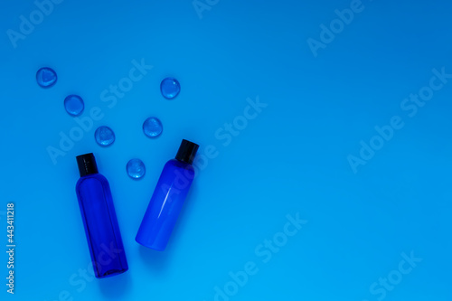 Cosmetic bottles with refreshing shampoo and lotion on a blue background, top view. Packaging for branded products.Blue on blue.