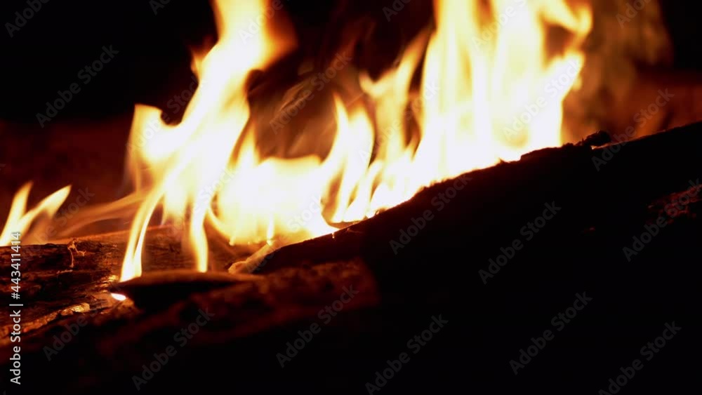 Night Bright Bonfire Burns in Forest. Hot tongues of flame, fire rise upward. Dry branches, logs burn and smolder in smoke on open fire. Red glow from fire in pit. Tourism. Camping. Slow-motion. 4K. Night Bright Bonfire Burns in Forest. Hot tongues of flame, fire rise upward. Dry branches, logs burn and smolder in smoke on open fire. Red glow from fire in pit. Tourism. Camping. Slow-motion. 4K.