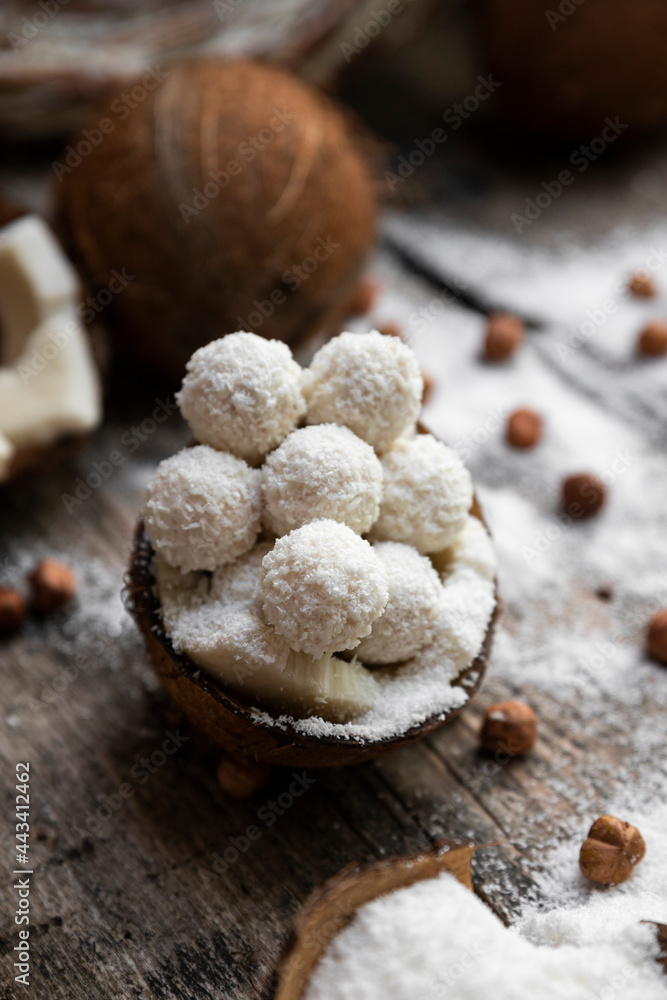 Fototapeta premium Coconut candy, balls, coconuts and hazelnuts on a rustic wooden surface