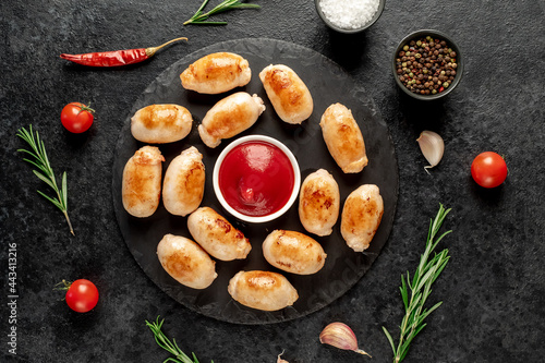 small grilled sausages on a stone background