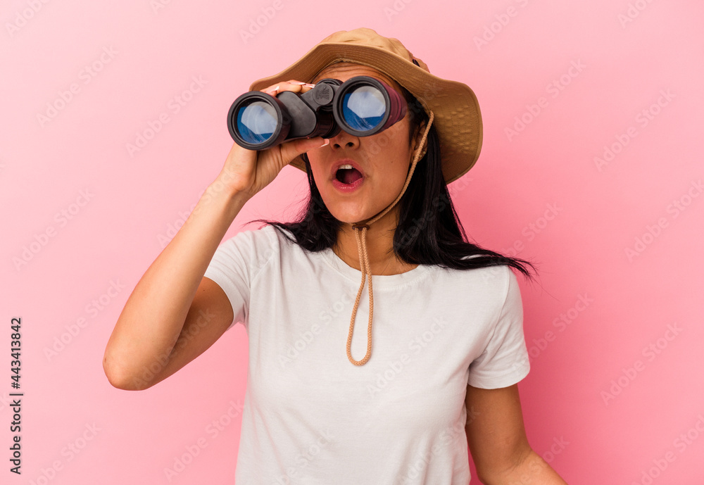 Young mixed race explorer woman holding binoculars isolated on pink background Young mixed race explorer woman holding binoculars isolated on pink background