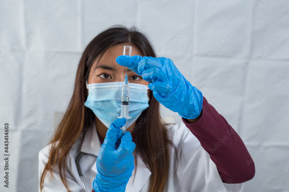 Asian female doctor holding vaccine and syringe, wearing protective equipment isolated on white background. Asian female doctor holding vaccine and syringe, wearing protective equipment isolated on white background.
