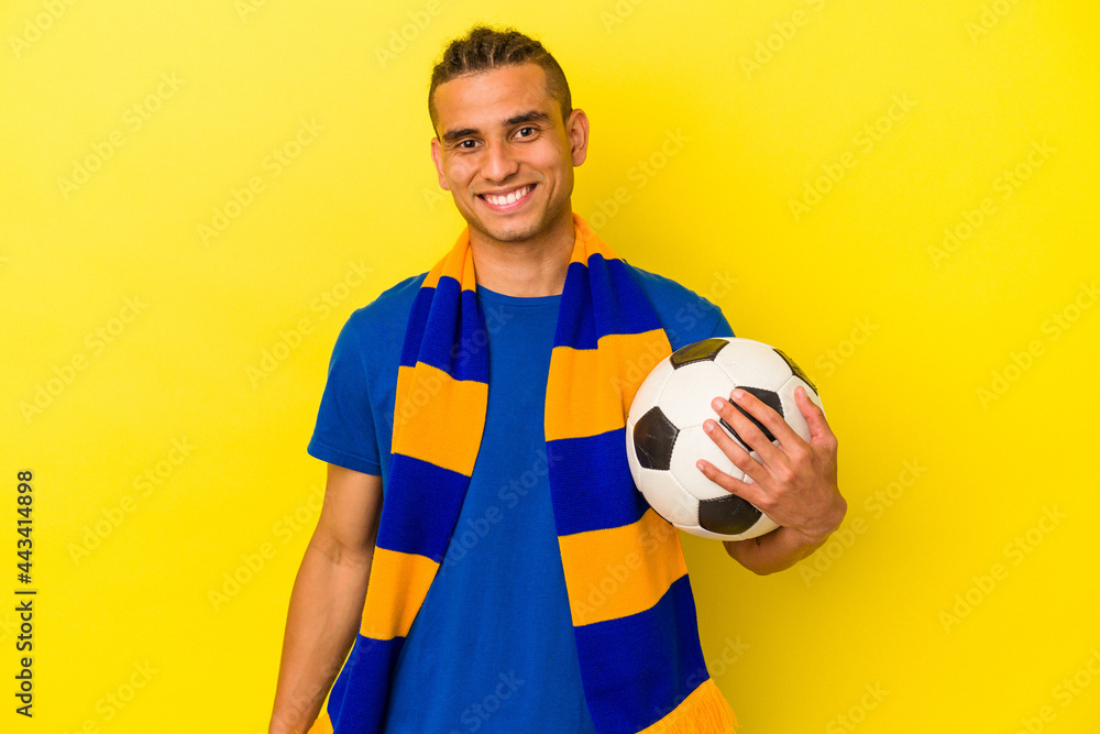 Young venezuelan man watching soccer isolated on yellow background happy, smiling and cheerful.