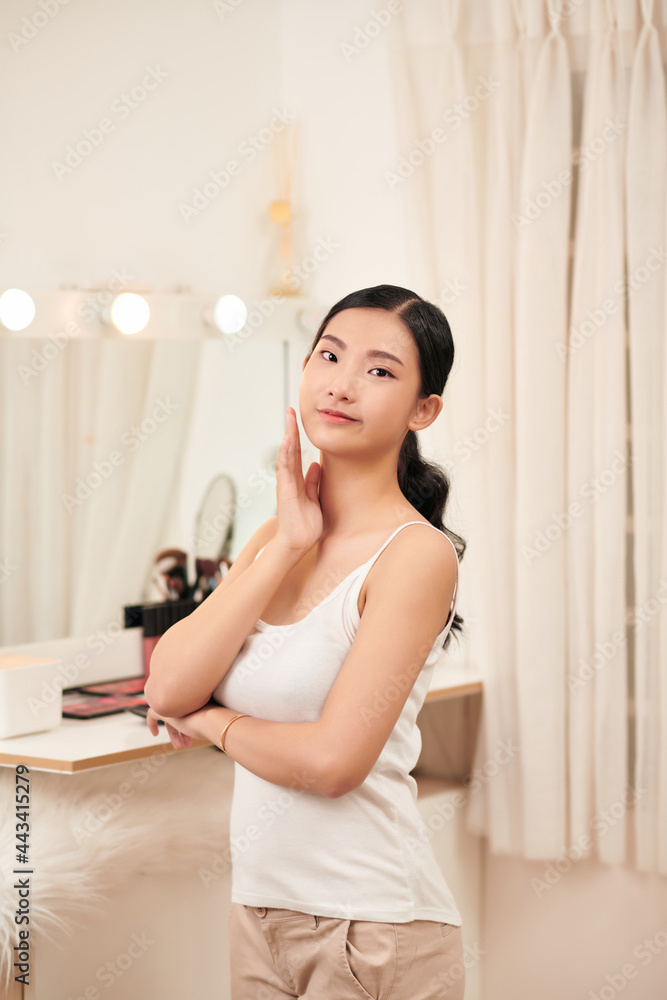Attractive Vietnamese woman looking at her face in the mirror Attractive Vietnamese woman looking at her face in the mirror