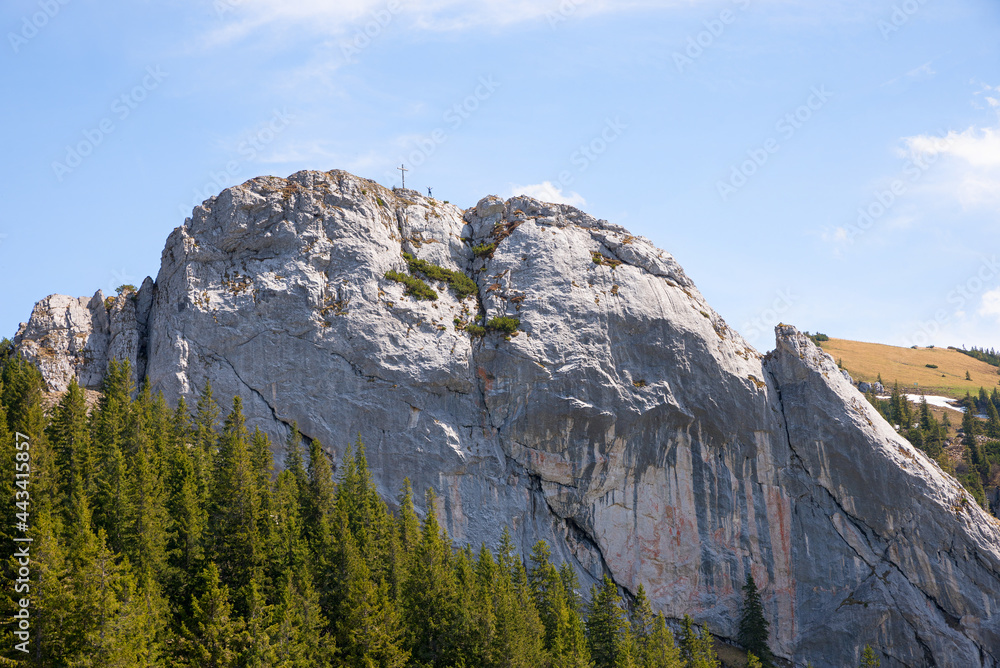 Summit of Taubenstein, girl beside the mountain cross, bavarian alps