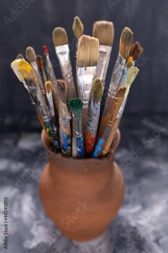 Paint brush in clay jug on abstract table background . Paintbrush for painting art still life