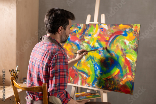 Male artist working on painting. Man artist painter in creative studio