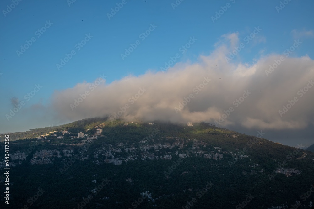 clouds covering the top of a green hill in the rural mountain area of Lebanon