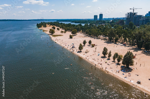 Aerial view of city ​​Beach. People sunbathe and relax near the water. Summer swimming in a river or sea. Sunny day . © Denis Chubchenko