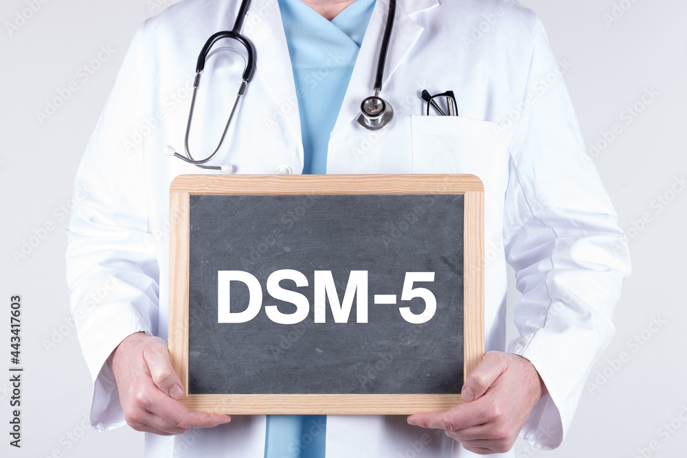 Doctor holding a blackboard with DSM-5 written on it Doctor holding a blackboard with DSM-5 written on it
