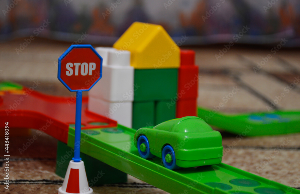 toy track with a car and a stop sign, the car stopped in front of the