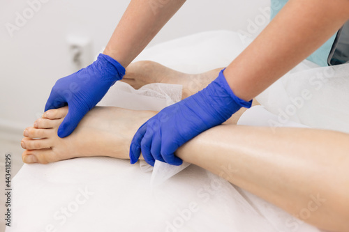 Doctor in gloves examining painful knee of female patient leg trauma. Healthcare medical insurance concept. Physiotherapist worker woman assisting physical medical exercise recovery after injuries