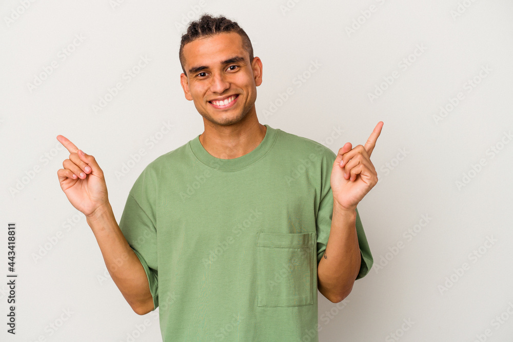 Young venezuelan man isolated on white background pointing to different copy spaces, choosing one of them, showing with finger. Young venezuelan man isolated on white background pointing to different copy spaces, choosing one of them, showing with finger.