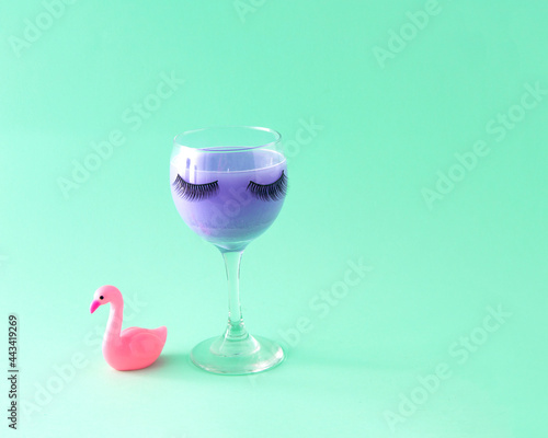 Glass with lashes and flamingo. Celebration. Female party. Turquoise background.