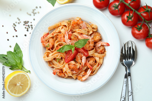 Plate of shrimp pasta and ingredients on white background