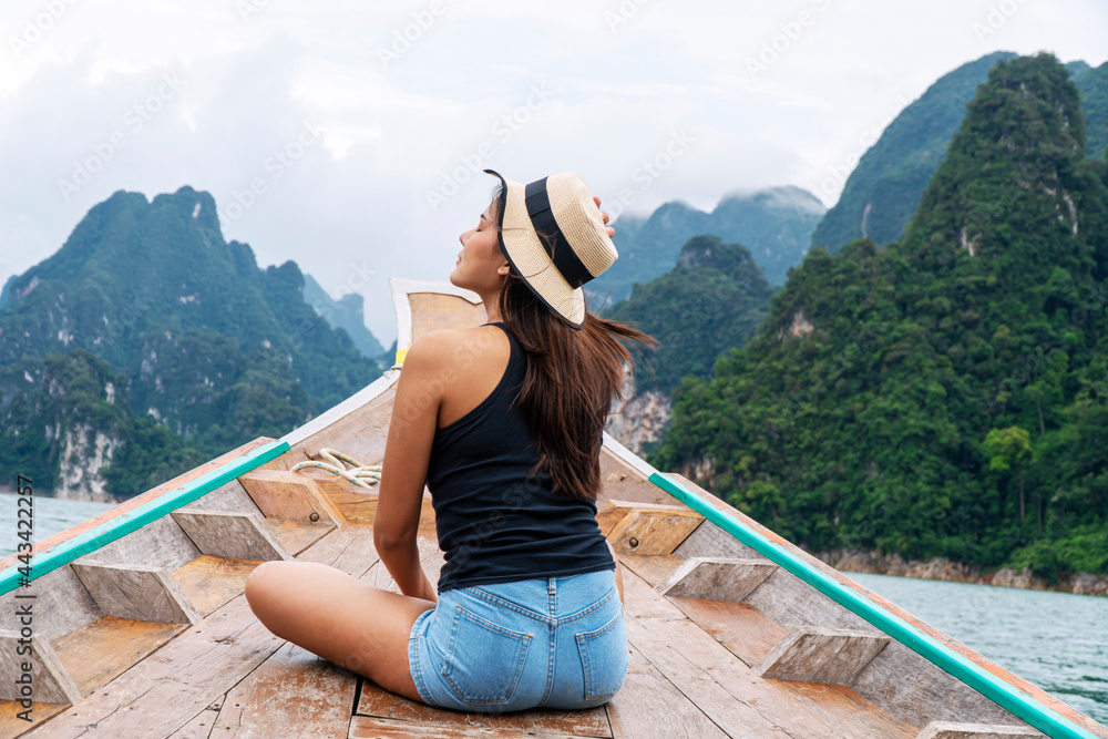 Adventure lifestyle vacationer relax concept. Traveler young woman wear hat sitting on long tail boat floating lagoon with mountains and sky while vacation tourist  at surat thani.