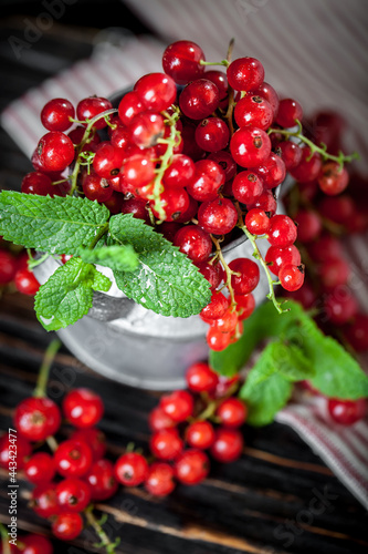 Ripe red currant berries in a bowl. Fresh red currants on dark rustic wooden table. Background with copy space. Selective focus.